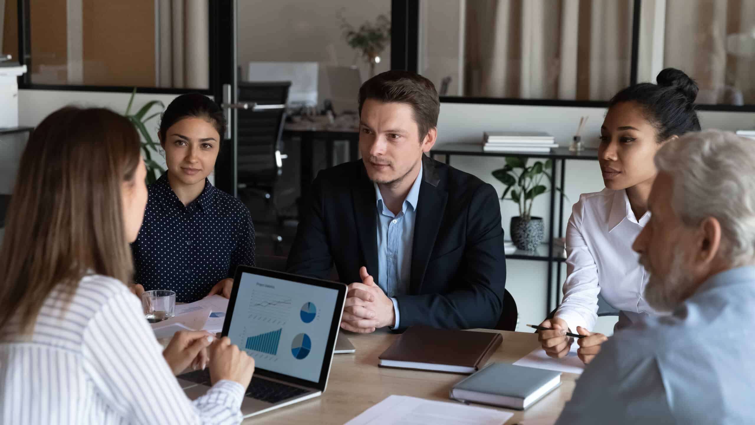 Diverse business partners sit at conference table talk develop strategy